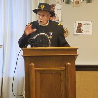Photo of a JCNYGS member in a historic uniform giving a speech at a podium